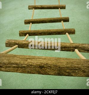 A perspective view of a rope ladder with wooden rungs on a children's climbing frame. Stock Photo