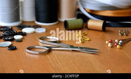 A close up perspective view a small pair of silver sewing scissors amongst an array of sewing accessories. Stock Photo