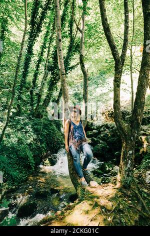 Young woman by the tree in the forest Stock Photo