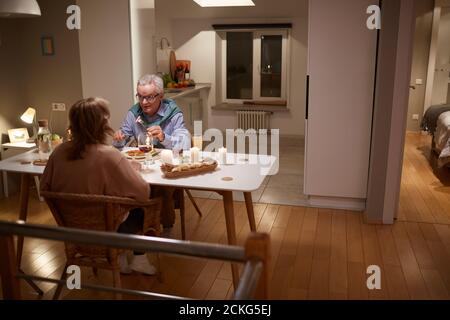 Family of two talking to each other during dinner in the evening at home Stock Photo