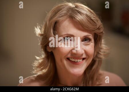 Close-up of beautiful mature woman with blond hair smiling at camera Stock Photo