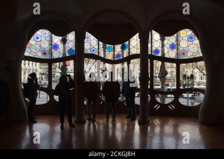 Visitors observe the large-scale stained-glass window in the central salon of the noble floor in the Casa Batlló in Barcelona, Catalonia, Spain. The mansion designed by Catalan modernist architect Antoni Gaudí for the Batlló family as a revenue house as well as a private family residence built was between 1904 and 1906. Stock Photo
