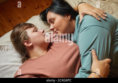 Two girlfriends lying on bed looking at each other they enjoying each other during leisure time Stock Photo