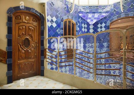 Wooden door of one of the apartments and the blue tiled lightwell in the Casa Batlló in Barcelona, Catalonia, Spain. The mansion designed by Catalan modernist architect Antoni Gaudí for the Batlló family as a revenue house as well as a private family residence built was between 1904 and 1906. Stock Photo