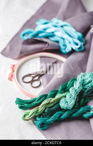 Set for embroidery. Linen fabric, patterns for embroidery, hoop, thread of green and blue colors and needles. Copy space, top view Stock Photo