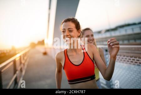 Beautiful happy women friends working out, exercising, running, jogging outdoor. Stock Photo