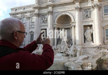 A man takes a picture at the Trevi fountain in Rome, February 15, 2016. Italy launched a United Nations-backed task force on Tuesday with a mission to protect monuments and cultural sites threatened by conflict and natural disaster around the world.  Picture taken on February 15, 2016. REUTERS/Stefano Rellandini