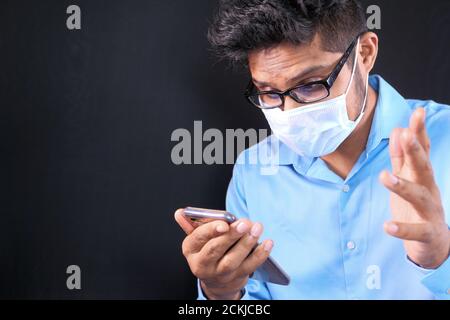 young man with face mask using smart phone indoor  Stock Photo