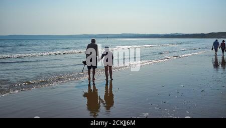An old couple paddling in the sea on the beach at Filey Cobble Landing, North Yorkshire east coast, northern England, UK Stock Photo