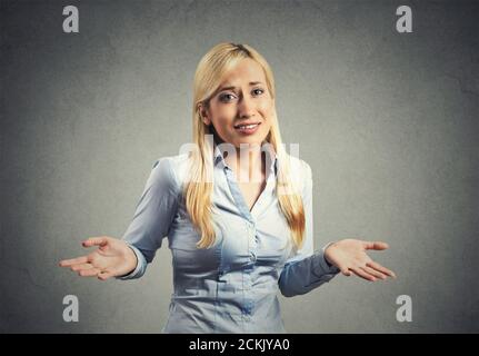 Portrait dumb looking woman arms out shrugs shoulders who cares so what I don't know isolated on gray wall background. Negative human emotion, facial Stock Photo
