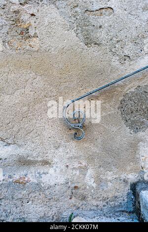Weathered wall exterior with detail of old wrought iron handrail with the stylized shape of a flying person Stock Photo