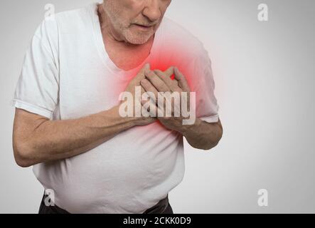 senior man suffering from bad pain in his chest isolated on gray background Stock Photo