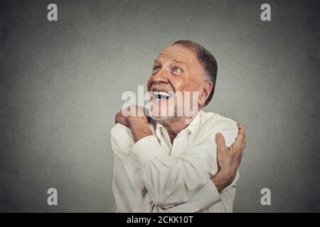 Closeup portrait confident smiling man holding hugging himself isolated on grey wall background. Positive human emotion, facial expression, feeling, r Stock Photo