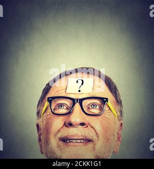 Closeup Portrait of Old Man with glasses looking up isolated on gray wall background with copy space Stock Photo