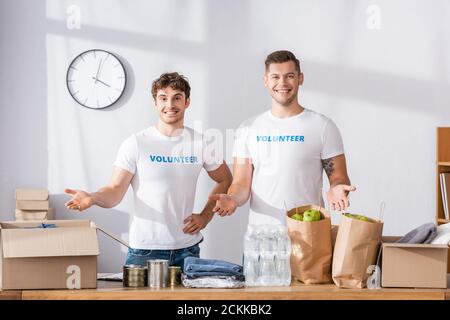 Volunteers pointing with hands at donations in charity center Stock Photo