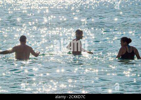 Miami Beach Florida,Atlantic Ocean water public seashore,silhouetted adults wading swimming man men woman ocean,visitors tourist vacation group people Stock Photo