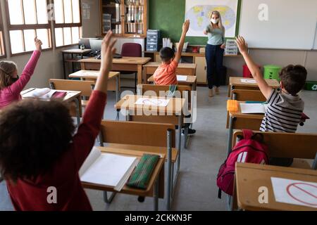 Group of kids raising their hands in the class at school Stock Photo