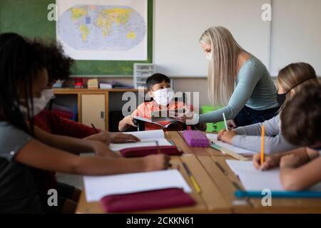 Female teacher wearing face mask teaching a disable boy wearing face mask at school Stock Photo