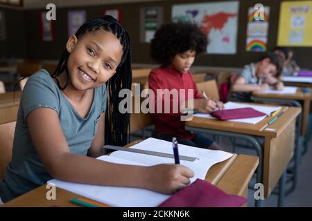 Portrait of girl smiling while sitting on her desk at school Stock Photo