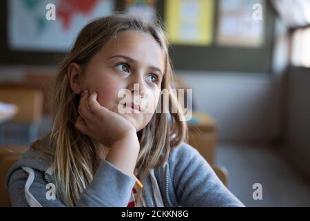 Girl sitting on her desk in class at school Stock Photo