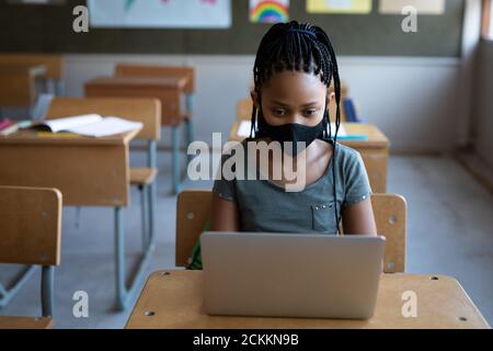 Girl wearing face mask using laptop on her desk at school Stock Photo