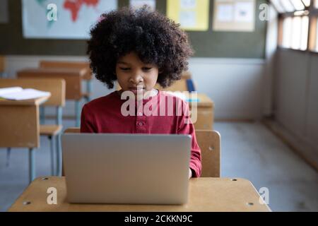 Boy using laptop while sitting on his desk in class at school Stock Photo