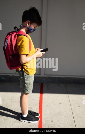 Boy wearing face mask using smartphone at school Stock Photo