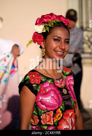 Portrait of Mexican young woman in flowery local dress and head band during Parade in Oaxaca, smiling Stock Photo