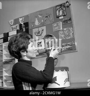 The presenter of childrens' television show Blue Peter is pictured with Little Ted in the BBC studio office in the early 1960s Stock Photo
