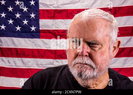 Vietnam Veteran Looking Away Suspiciously While In Front Of American Flag Stock Photo