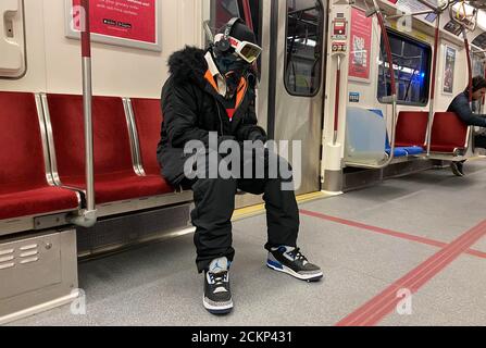 A man wearing ski goggles, gloves and clothing rides the subway during the global outbreak of coronavirus disease (COVID-19) in Toronto, Ontario, Canada March 31, 2020. Picture taken March 31, 2020.  REUTERS/Chris Helgren