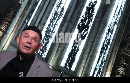 16 September 2020, Saxony-Anhalt, Magdeburg: The Dresden artist Max Uhlig sits in front of monochromatic choir windows at the ceremony for the inauguration of the windows for the Magdeburg Johanniskirche. The 14th and last window by the Dresden artist was installed from 20 July 2020. Between 2014 and 2017, 13 mouth-blown glass windows were already installed in St. John's Church in Magdeburg, including six stained glass windows of an abstracted coloured landscape and seven figurative vine motifs as grisailles (monochromatic stained glass) in the choir. Photo: Ronny Hartmann/dpa-Zentralbild/dpa Stock Photo