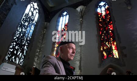 16 September 2020, Saxony-Anhalt, Magdeburg: The Dresden artist Max Uhlig sits in front of a monochromatic choir window and two colourful south windows during the ceremony for the inauguration of the windows for the Magdeburg Johanniskirche. The 14th and last window by the Dresden artist was installed from 20 July 2020. Between 2014 and 2017, 13 mouth-blown glass windows were already installed in St. John's Church in Magdeburg, including six stained glass windows of an abstracted coloured landscape and seven figurative vine motifs as grisailles (monochromatic stained glass) in the choir. Photo Stock Photo