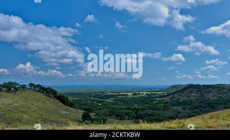 Rolling hills wine country central texas with lush green grasslands and forests with puffy white clouds in a blue sky on hot summer day. Stock Photo