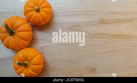 Miniature pumpkins on a wooden background. Template with copy space for Halloween or autumn. Stock Photo