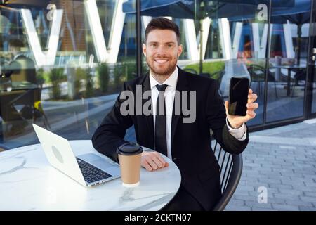 Businessman Working on Terrace outdoors Showing Phone. Freelance Businessman Stock Photo