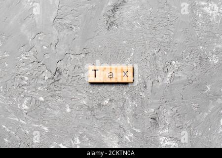 Tax word written on wood block. Tax text on cement table for your desing, concept. Stock Photo