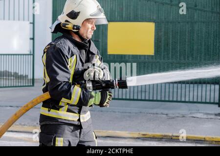 Fireman in action with water hose Stock Photo - Alamy