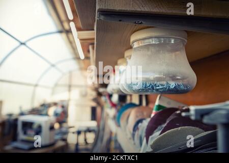 Woodwork workshop interior with many different tools and equipment. Plastic jars with many different screws nails suspended attached on shelf for Stock Photo