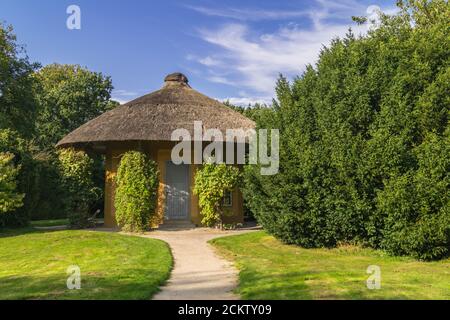 Beautiful pavilion or garden house in public garden park. Nice summer day with blooing trees and green grass. Stock Photo