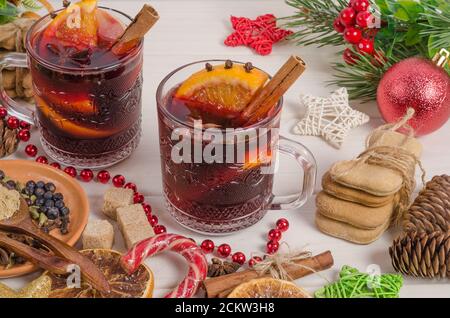 Mulled wine with orange slice, apple, cinnamon stick on a white wooden background. Stock Photo