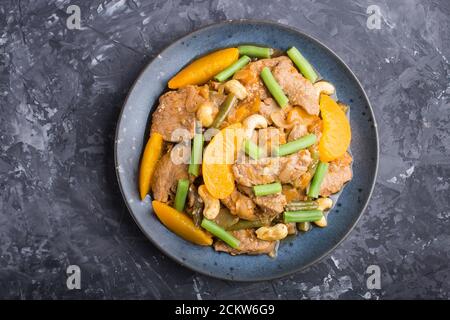 Fried pork with peaches, cashew and green beans on a black concrete background. Top view, close up, flat lay. chinese cuisine. Stock Photo