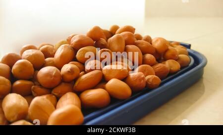 Indian organic peanuts isolated on blue container cap with flat surface with selective focus. Stock Photo