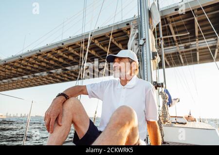 Mature man looking away while sitting on his sailboat Stock Photo