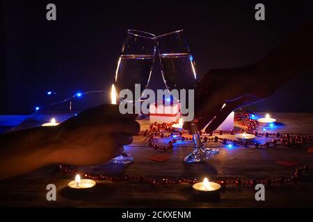Young couple with glasses of champagne in hands close-up. Romantic candlelit dinner at the table. concept of the celebration, engagement Stock Photo