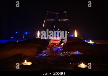 Young couple with glasses of champagne in hands close-up. Romantic candlelit dinner at the table. concept of the celebration, engagement Stock Photo