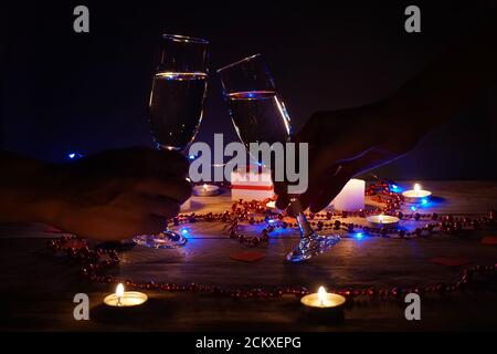 Young couple with glasses of champagne in hands close-up. Romantic candlelit dinner at the table. concept of the celebration, engagement Stock Photo