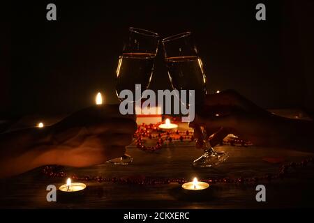 Young couple with glasses of champagne in hands close-up. Romantic candlelit dinner at the table. concept of the celebration, engagement Stock Photo
