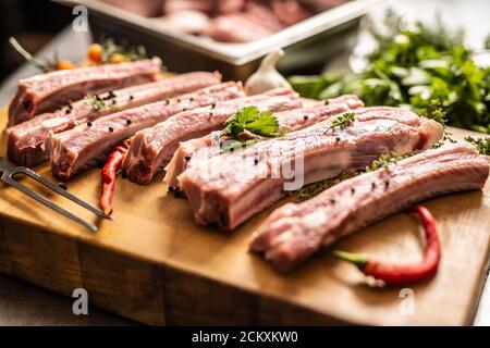 Raw seasoned spare ribs on a cutting board with chillies next to it Stock Photo