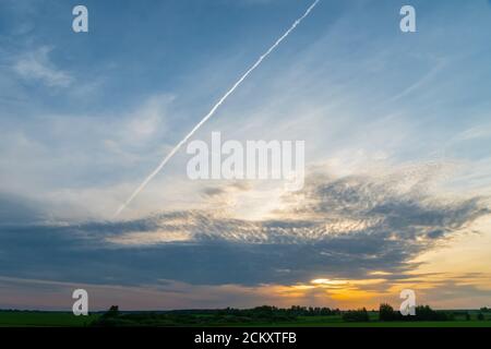 Beautiful evening sky with clouds during sunset. Trail from the plane on the background of a beautiful sky. Beautiful sky background during sunset Stock Photo